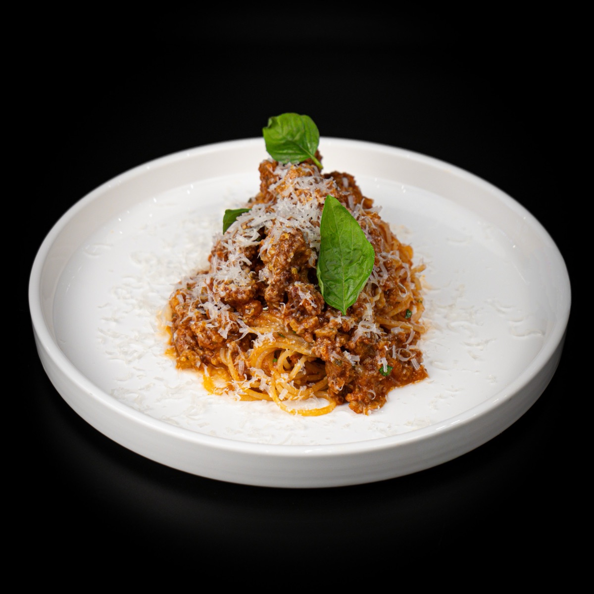 Spaghetti with meat sauce, grated cheese and basil
