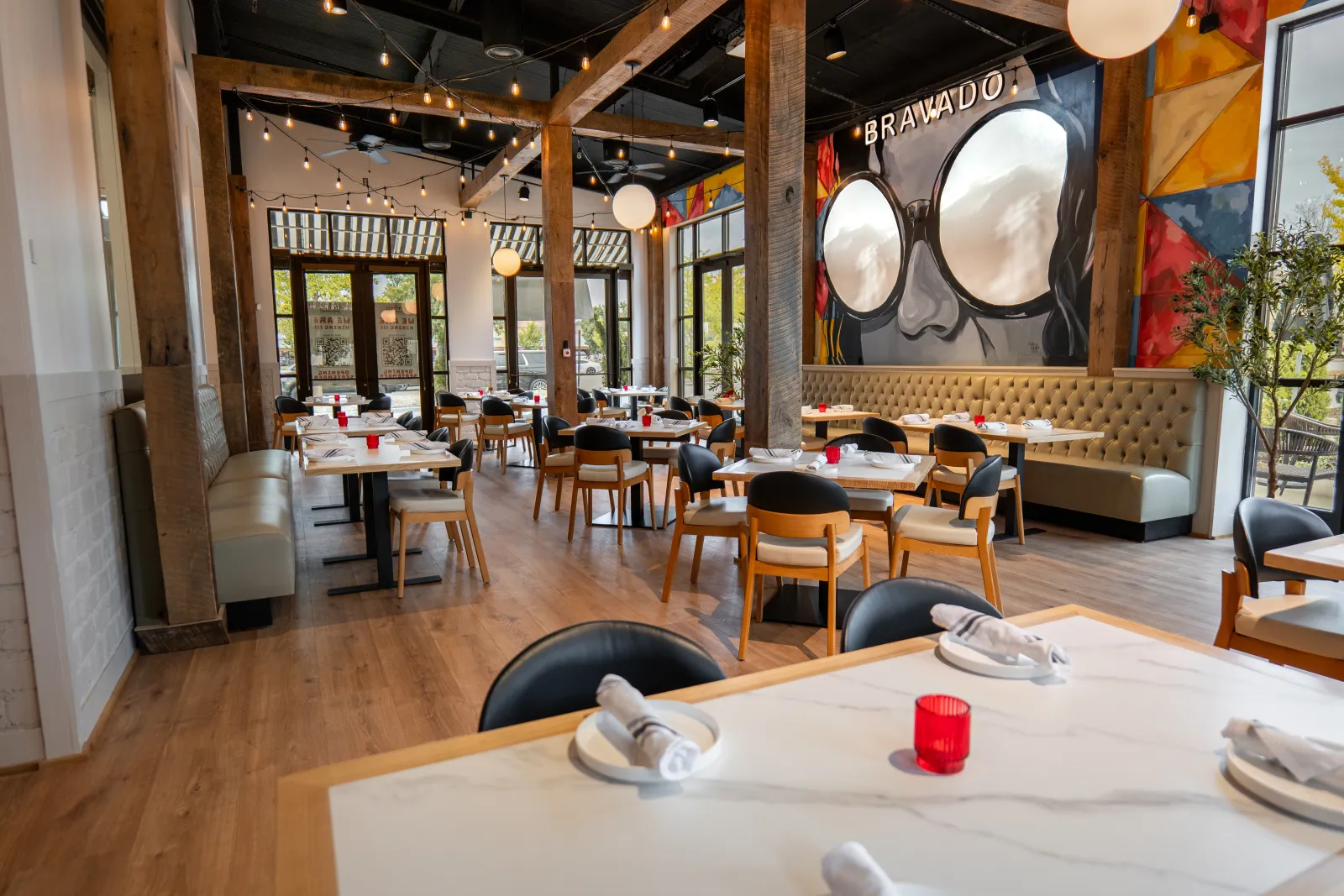 The Sunroom at Bravado: the full room with tables, string lights and the sunglasses mural